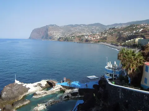 Praia Formosa’s shoreline curves toward the cliffs, seen from Doca do Cavacas along the coastal walk.